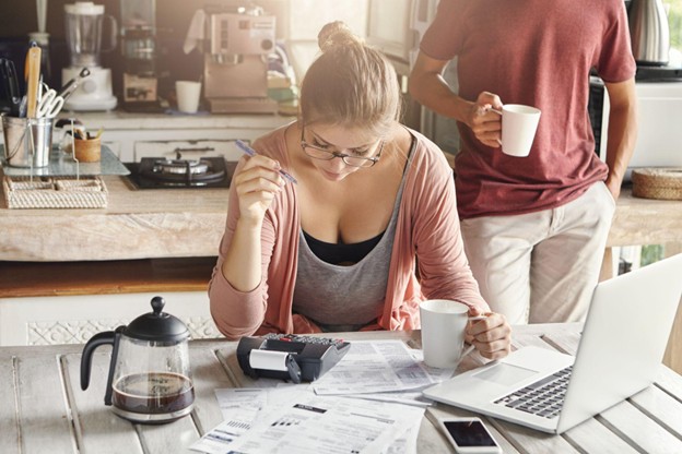 Lady in a coffeeshop managing her finances, cofee in hand, laptop and papers on table